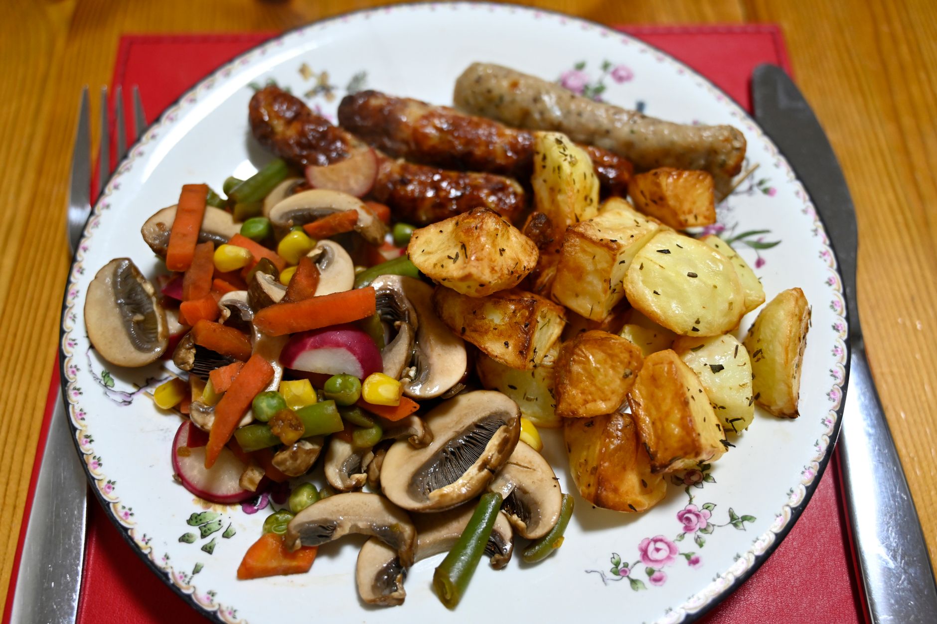 Delicious plate featuring sausages, roasted potatoes, and mixed vegetables for a hearty meal.